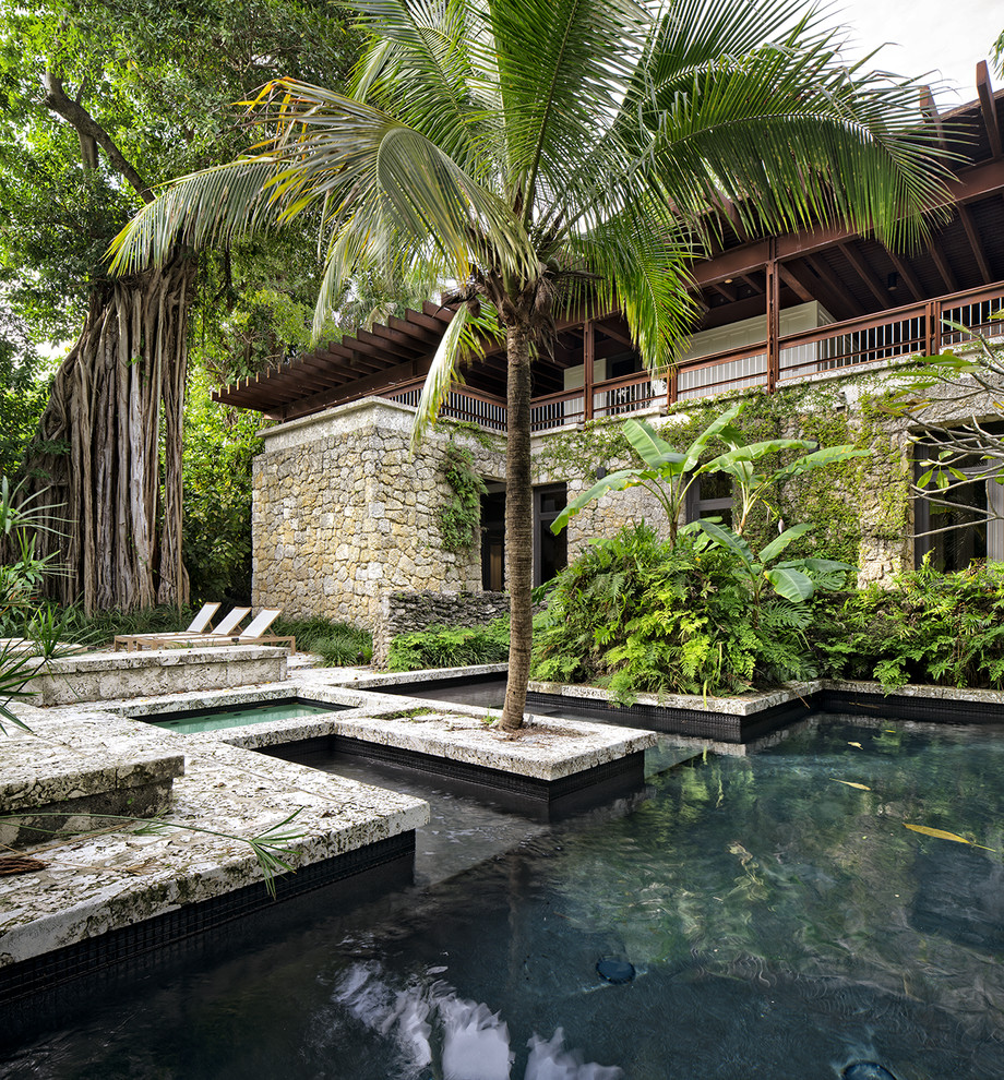 Design ideas for a large tropical backyard custom-shaped pool in Miami with a hot tub and tile.