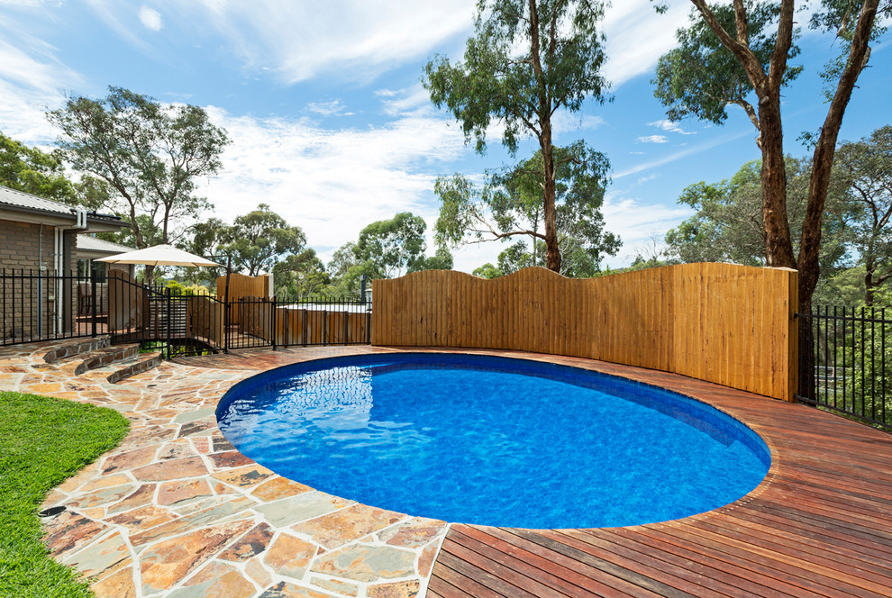 Inspiration for a mid-sized contemporary backyard round natural pool in Melbourne with a water feature and decking.