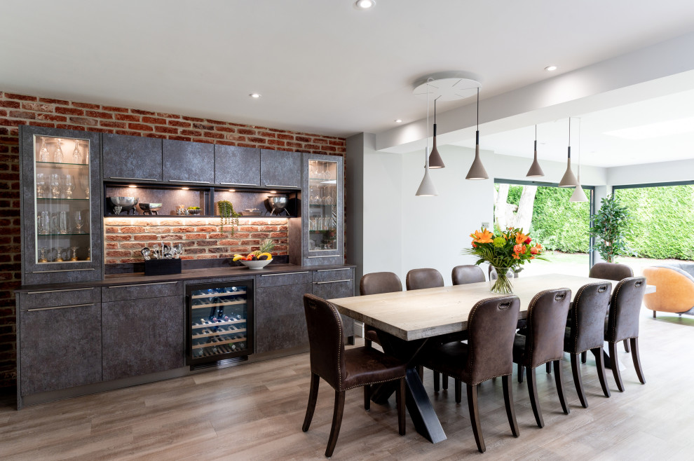 Photo of a large contemporary u-shaped open plan kitchen in Surrey with an integrated sink, flat-panel cabinets, grey cabinets, quartzite benchtops, metallic splashback, glass sheet splashback, black appliances, vinyl floors, grey floor and white benchtop.