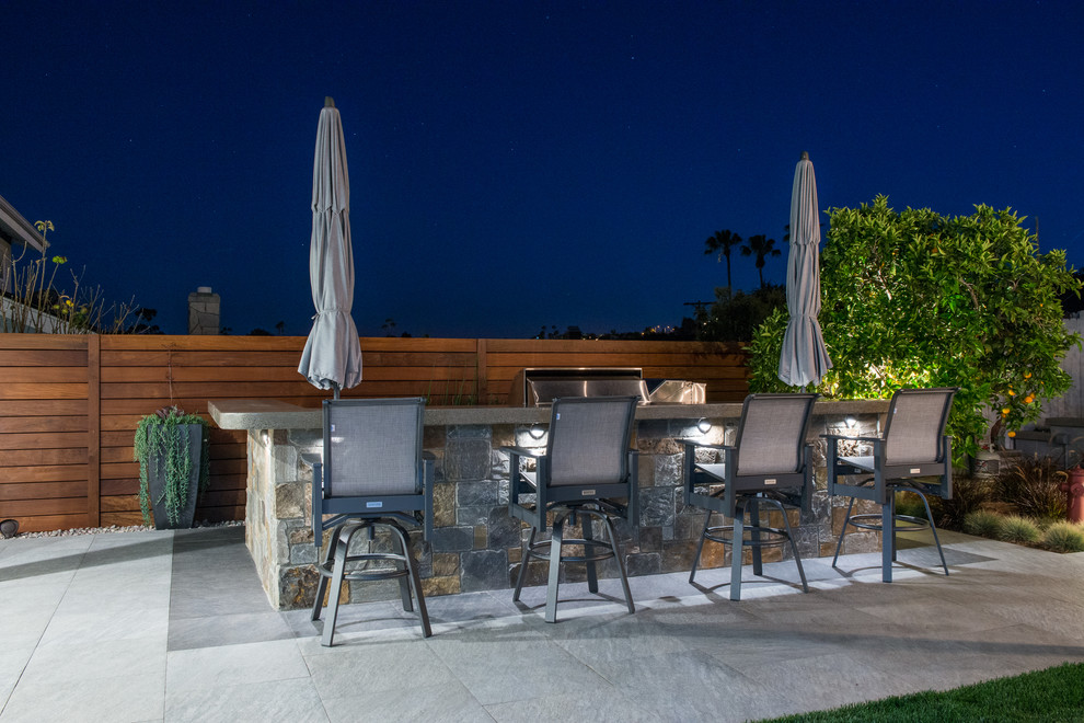 Design ideas for a large transitional backyard patio in Orange County with with fireplace and natural stone pavers.