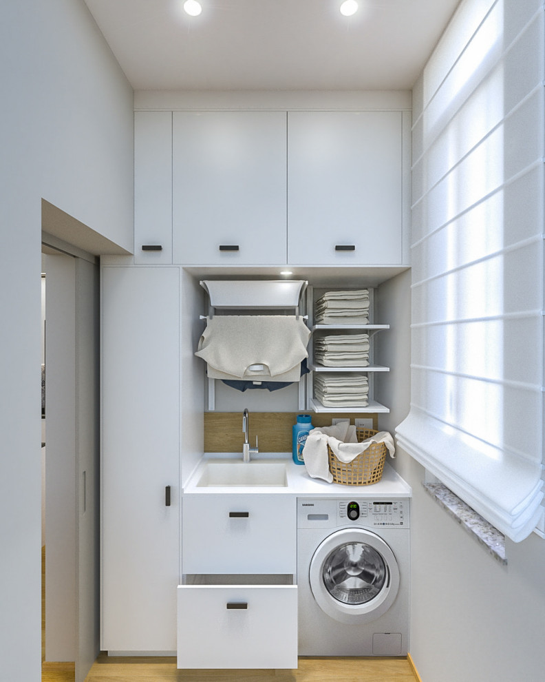Inspiration for a small contemporary single-wall dedicated laundry room in Milan with a single-bowl sink, flat-panel cabinets, white cabinets, laminate benchtops, grey walls, porcelain floors, an integrated washer and dryer and white benchtop.