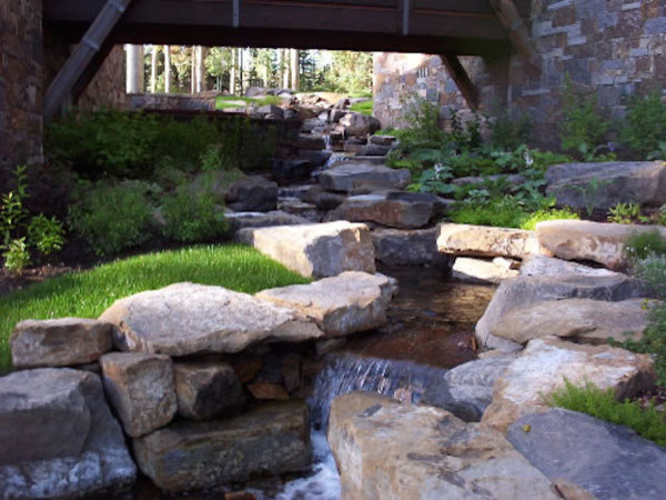 Photo of a huge rustic full sun backyard stone water fountain landscape in Denver.