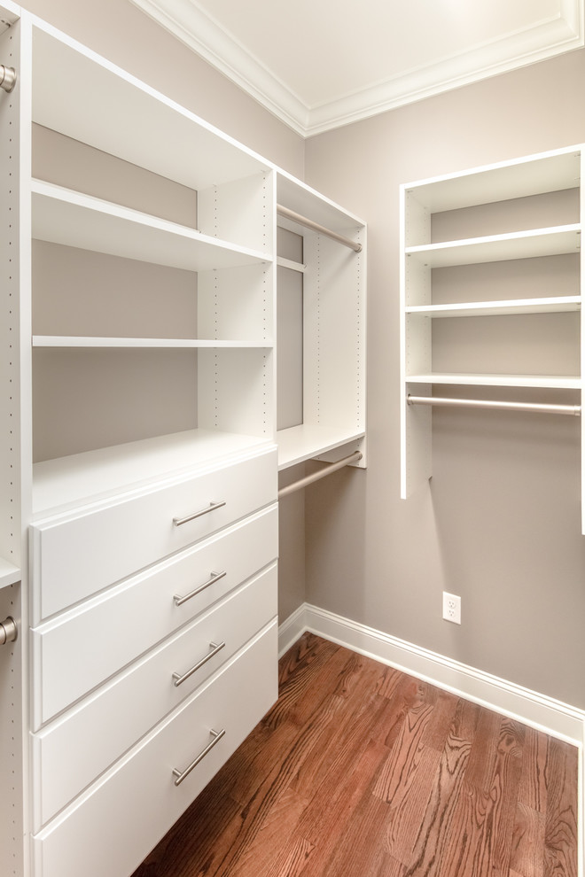 Inspiration for a mid-sized transitional gender-neutral dark wood floor walk-in closet remodel with flat-panel cabinets and white cabinets