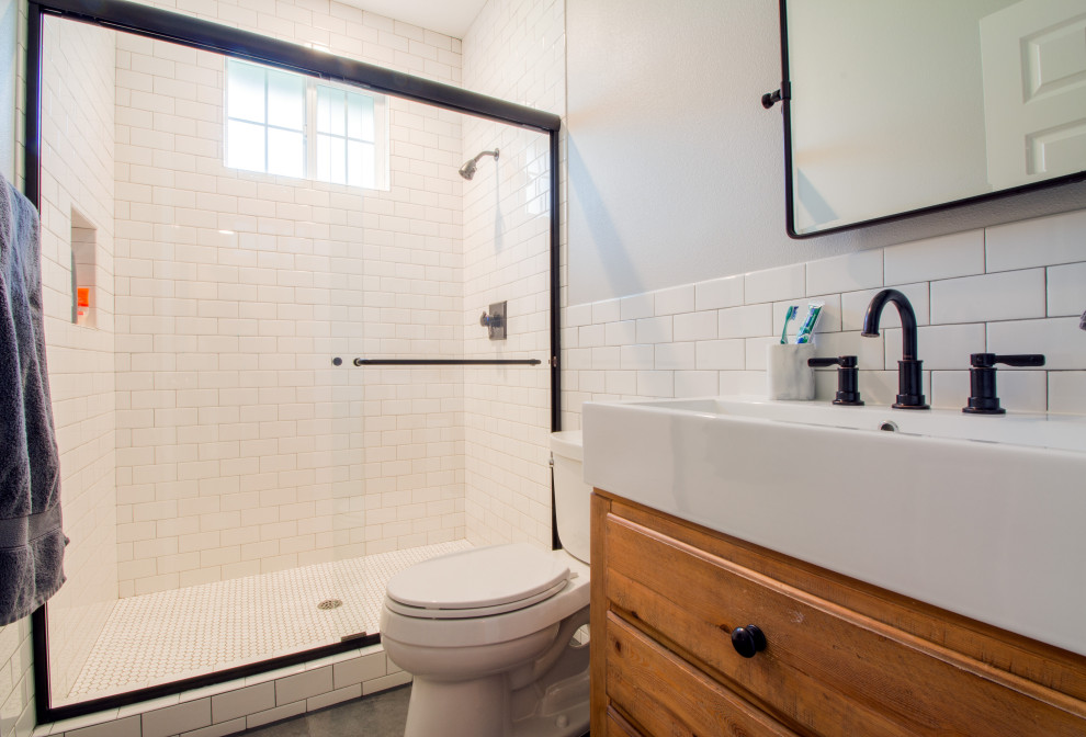 Inspiration for a mid-sized 3/4 bathroom in Orange County with furniture-like cabinets, medium wood cabinets, white tile, subway tile, white walls, a vessel sink, grey floor and a sliding shower screen.