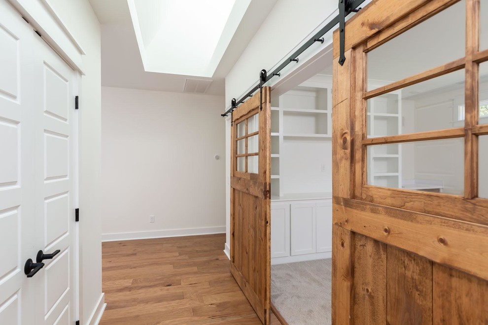 Design ideas for a large country hallway in Raleigh with white walls, medium hardwood floors and brown floor.