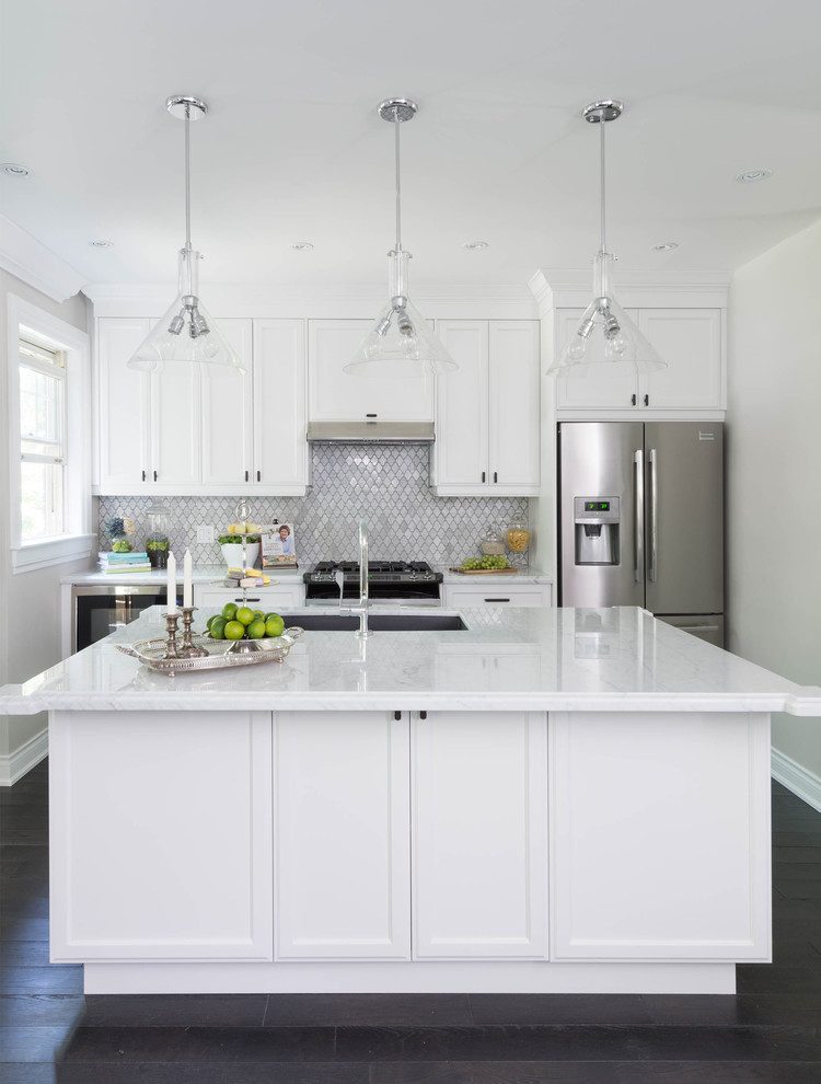 Example of a mid-sized transitional galley dark wood floor and brown floor open concept kitchen design in Toronto with an undermount sink, recessed-panel cabinets, white cabinets, marble countertops, white backsplash, stone tile backsplash, stainless steel appliances, an island and gray countertops