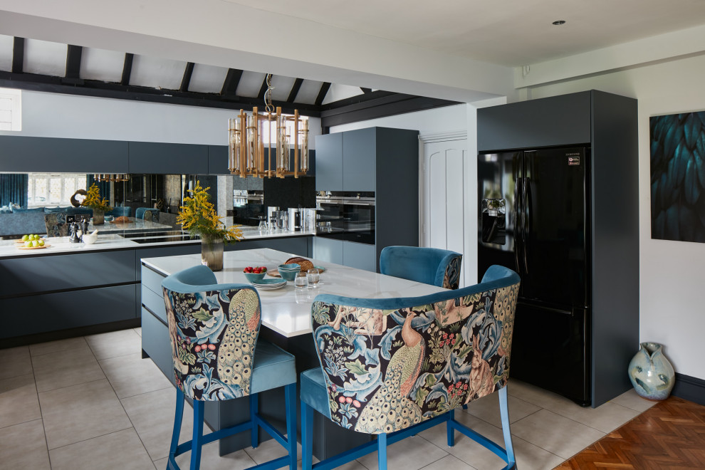 Inspiration for a mid-sized modern u-shaped exposed beam eat-in kitchen remodel in London with a drop-in sink, flat-panel cabinets, gray cabinets, solid surface countertops, mirror backsplash, black appliances, an island and white countertops