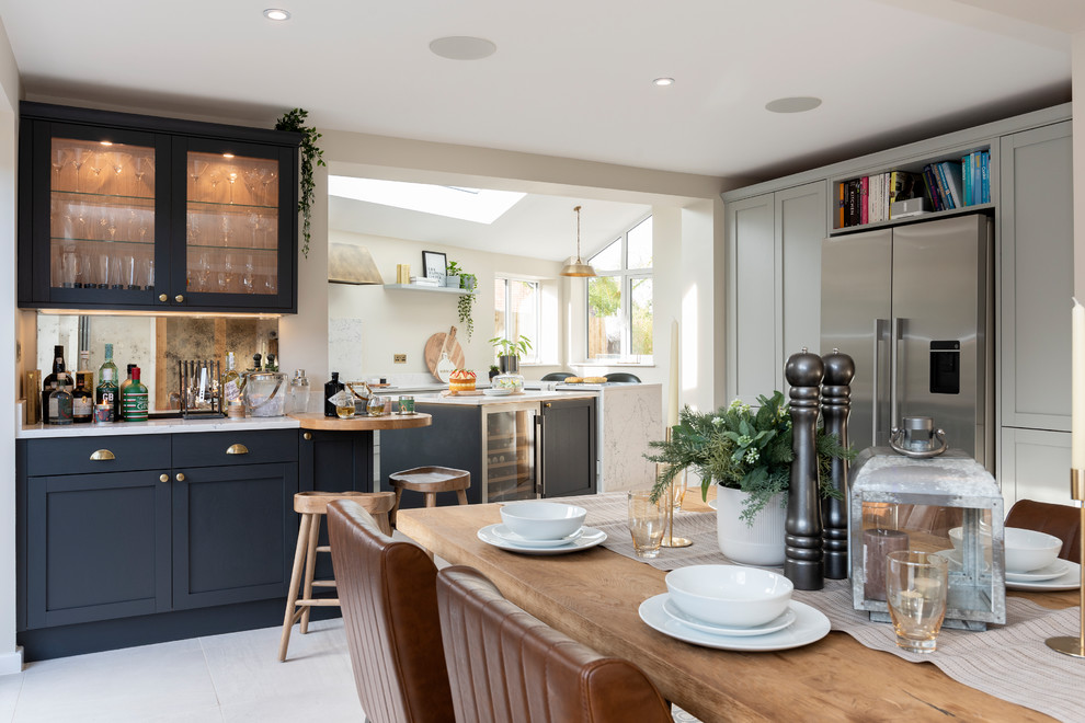 Inspiration for a large contemporary galley eat-in kitchen in West Midlands with a drop-in sink, shaker cabinets, grey cabinets, marble benchtops, black appliances, ceramic floors, with island, white floor and white benchtop.