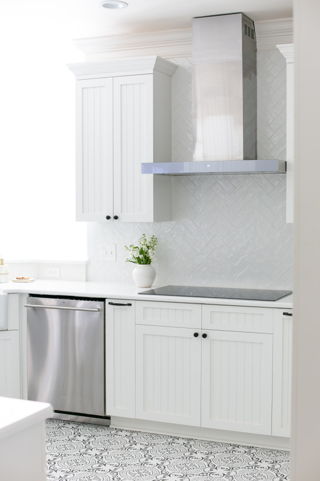 Example of a large transitional porcelain tile and white floor open concept kitchen design with a farmhouse sink, beaded inset cabinets, white cabinets, quartzite countertops, white backsplash, porcelain backsplash, stainless steel appliances and white countertops