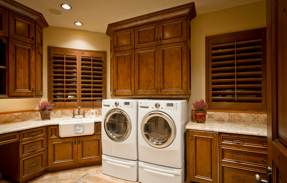 Expansive u-shaped dedicated laundry room in Phoenix with granite benchtops, beige walls, raised-panel cabinets, dark wood cabinets, medium hardwood floors, a side-by-side washer and dryer and a farmhouse sink.