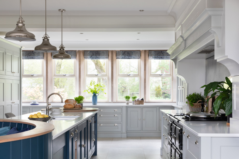 This is an example of a large traditional open plan kitchen in Manchester with an integrated sink, shaker cabinets, black cabinets, quartzite benchtops, metallic splashback, mirror splashback, stainless steel appliances, limestone floors, multiple islands, grey floor, white benchtop and coffered.