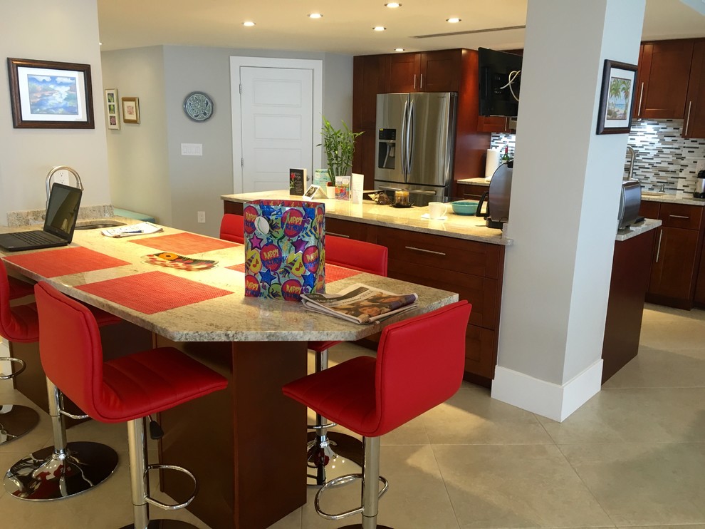 Example of a mid-sized transitional single-wall beige floor kitchen design in Miami with an undermount sink, shaker cabinets, medium tone wood cabinets, stainless steel appliances, an island, limestone countertops, gray backsplash and matchstick tile backsplash