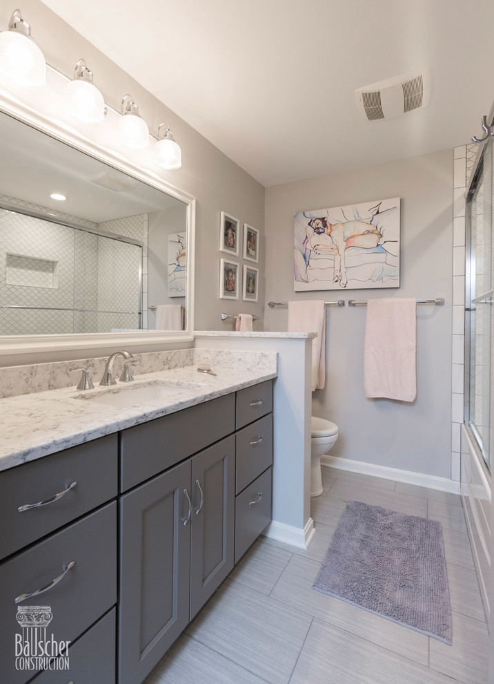 Inspiration for a small traditional kids bathroom in Cincinnati with flat-panel cabinets, grey cabinets, an alcove tub, a shower/bathtub combo, a one-piece toilet, white tile, porcelain tile, grey walls, porcelain floors, an undermount sink, granite benchtops, grey floor, a sliding shower screen and grey benchtops.
