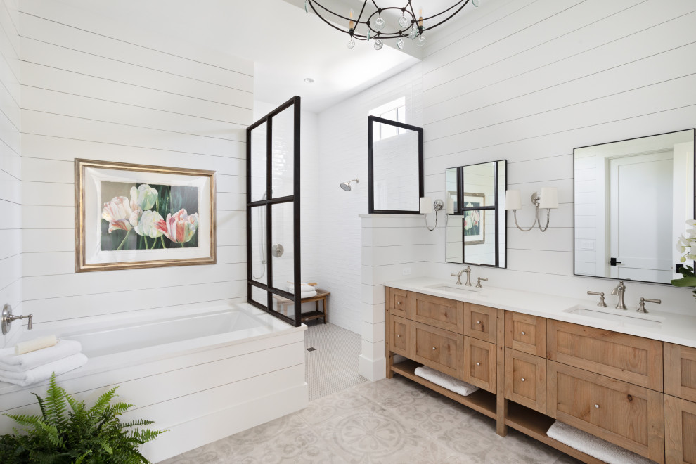 This is an example of a large beach style master bathroom in Tampa with recessed-panel cabinets, medium wood cabinets, a drop-in tub, a curbless shower, white walls, mosaic tile floors, a drop-in sink, grey floor, an open shower, white benchtops, a shower seat, a double vanity, a built-in vanity and planked wall panelling.