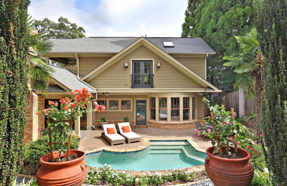 This is an example of a large arts and crafts backyard custom-shaped pool in Atlanta with brick pavers.