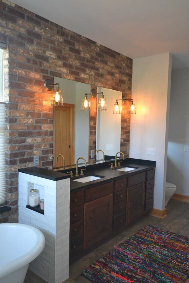 Mid-sized country master bathroom in Other with soapstone benchtops, a freestanding tub, a curbless shower, beige tile, porcelain tile, porcelain floors, flat-panel cabinets, dark wood cabinets, white walls, an undermount sink and brown floor.