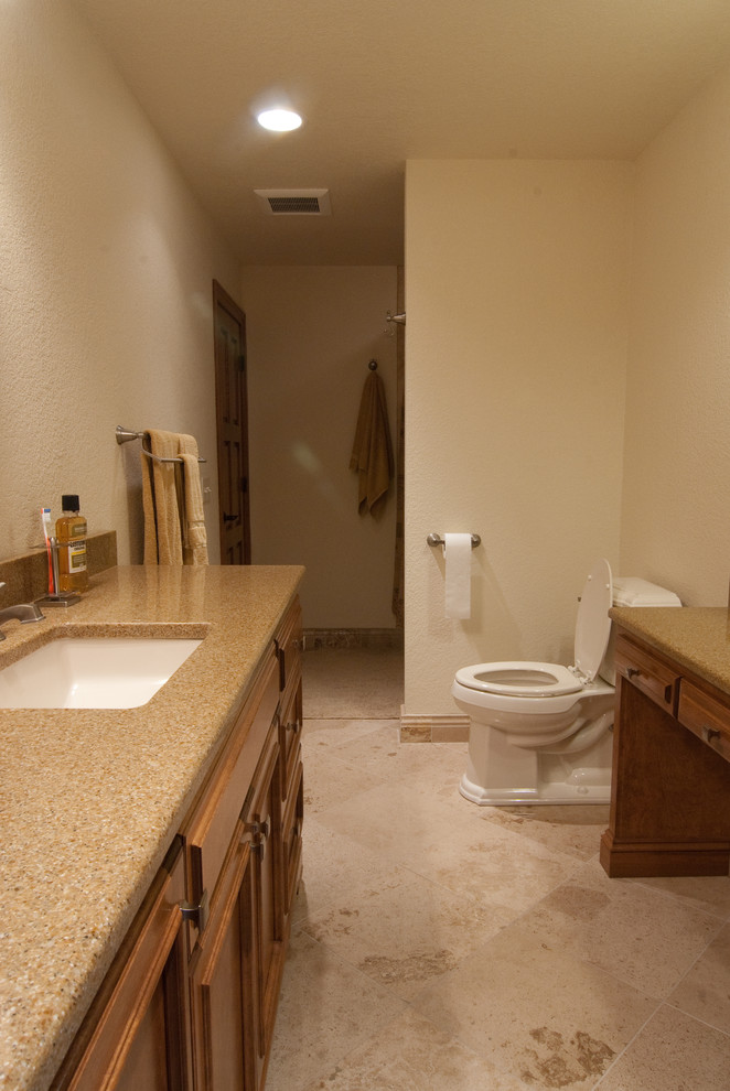 Design ideas for a mid-sized transitional master bathroom in Milwaukee with recessed-panel cabinets, brown cabinets, an undermount tub, a shower/bathtub combo, a one-piece toilet, brown tile, beige walls, travertine floors, an undermount sink, granite benchtops, brown floor and a shower curtain.