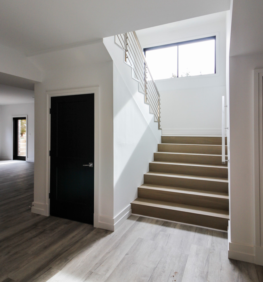 Diseño de escalera suspendida minimalista de tamaño medio con escalones de madera, contrahuellas de madera, barandilla de metal y machihembrado