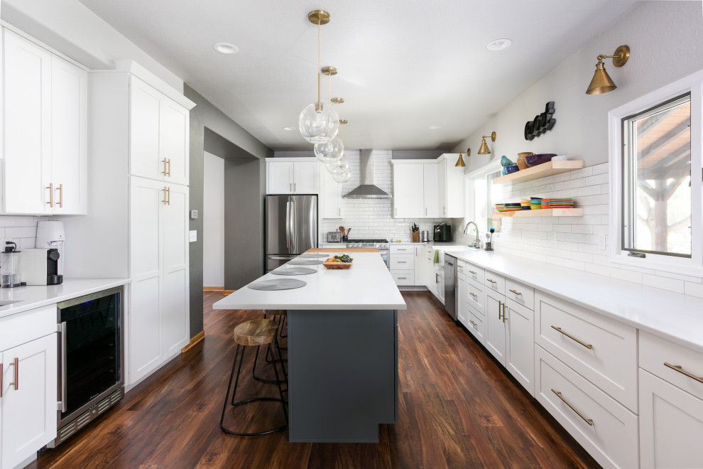 Inspiration for a large transitional u-shaped dark wood floor eat-in kitchen remodel in Denver with a farmhouse sink, shaker cabinets, white cabinets, quartz countertops, white backsplash, porcelain backsplash, stainless steel appliances, an island and white countertops