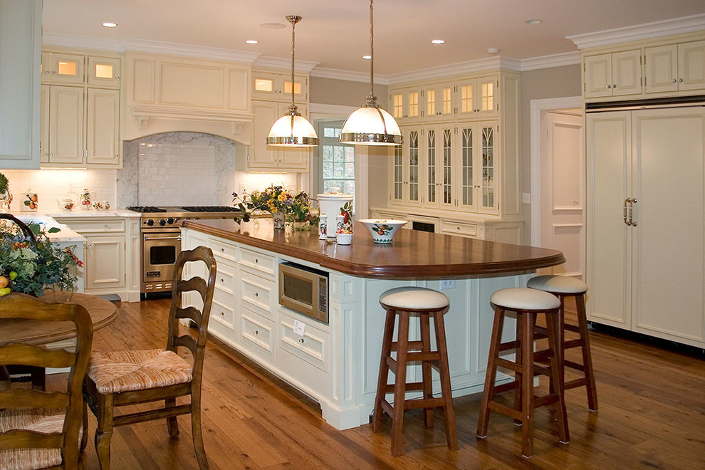 Inspiration for a large traditional l-shaped open plan kitchen in New York with an undermount sink, recessed-panel cabinets, white cabinets, panelled appliances, dark hardwood floors, with island and brown floor.
