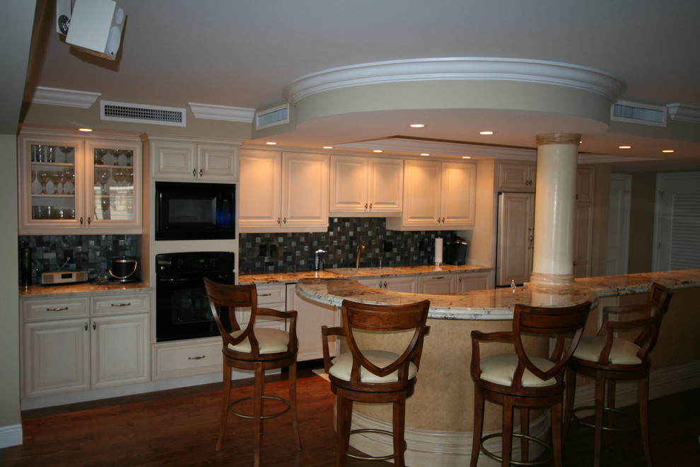 Eat-in kitchen photo in Miami with an undermount sink, raised-panel cabinets, beige cabinets, quartzite countertops, gray backsplash, glass tile backsplash, stainless steel appliances and an island