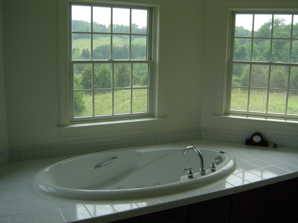 Drop-in bathtub - large master double-sink drop-in bathtub idea with recessed-panel cabinets, brown cabinets, a built-in vanity, a two-piece toilet, white walls, an integrated sink, a hinged shower door and white countertops