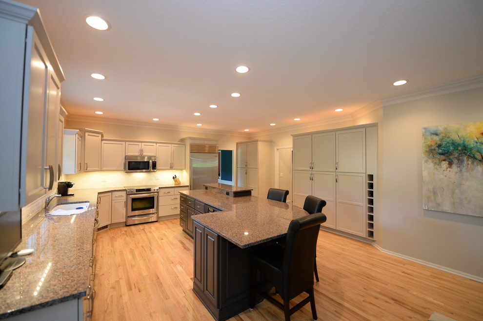 This is an example of a large transitional l-shaped eat-in kitchen in Other with recessed-panel cabinets, white cabinets, stainless steel appliances and with island.