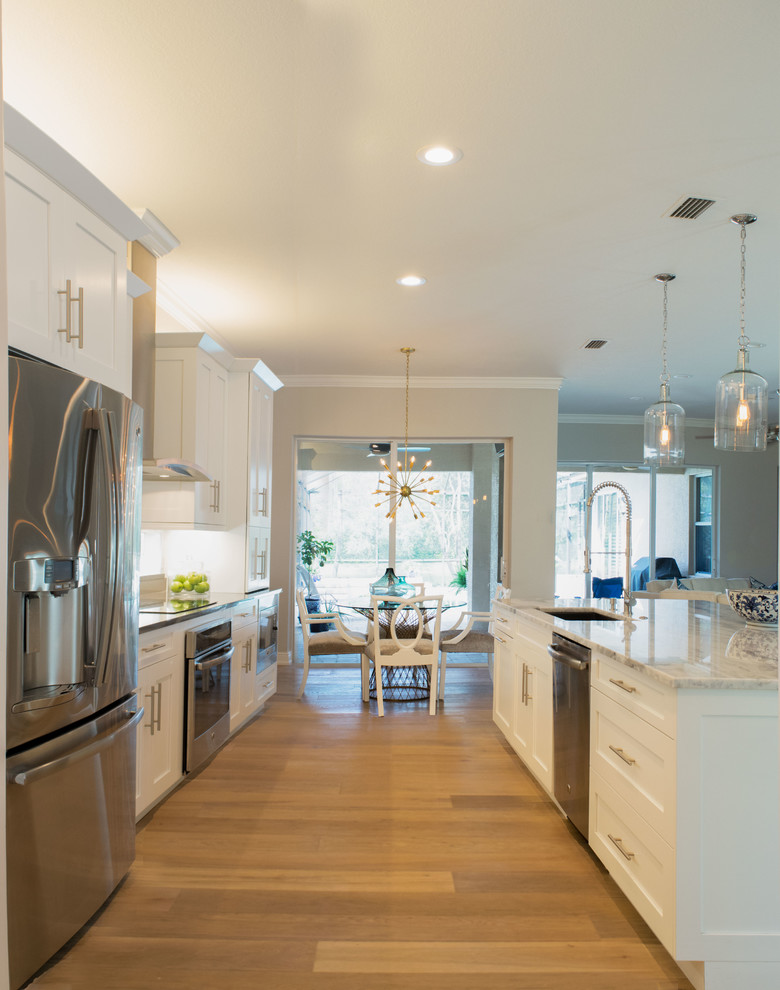 Open concept kitchen - mid-sized transitional single-wall light wood floor and beige floor open concept kitchen idea in Miami with shaker cabinets, white cabinets, marble countertops, white backsplash, stainless steel appliances, an island, an undermount sink and subway tile backsplash