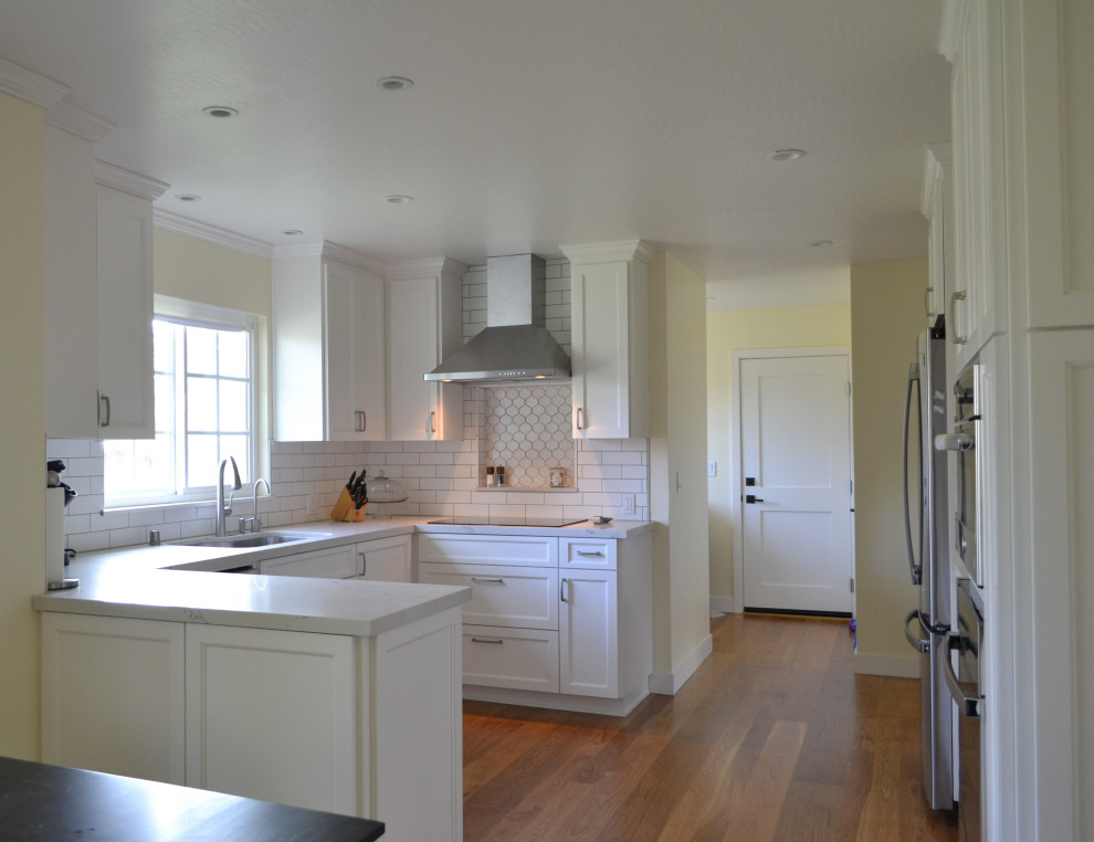 Design ideas for a mid-sized country u-shaped eat-in kitchen in San Francisco with an undermount sink, recessed-panel cabinets, white cabinets, quartz benchtops, white splashback, subway tile splashback, stainless steel appliances, medium hardwood floors and brown floor.