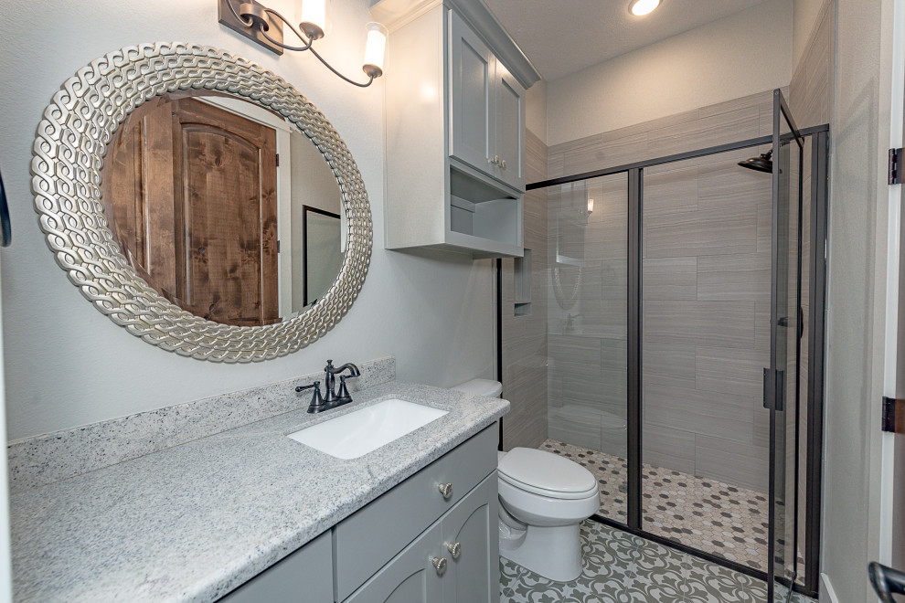 Idéer för stora amerikanska grått badrum med dusch, med skåp i shakerstil, grå skåp, en dusch i en alkov, en toalettstol med separat cisternkåpa, grå kakel, porslinskakel, grå väggar, cementgolv, ett undermonterad handfat, granitbänkskiva, grått golv och dusch med gångjärnsdörr