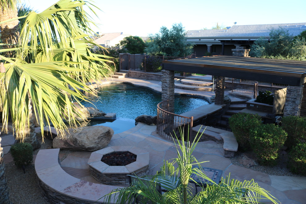 Example of a large classic backyard stone and custom-shaped natural hot tub design in Phoenix
