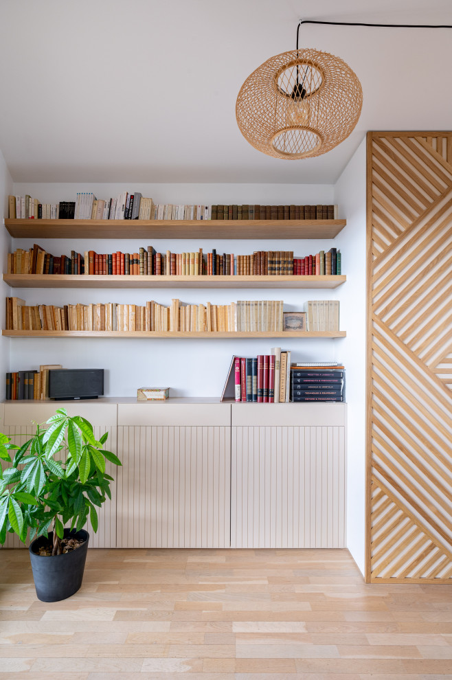 Идея дизайна: большая открытая гостиная комната в скандинавском стиле с с книжными шкафами и полками, бежевыми стенами, светлым паркетным полом, телевизором на стене и деревянными стенами