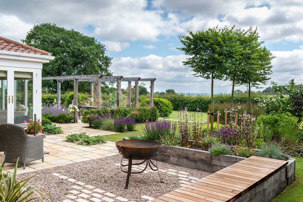 Mid-sized country backyard garden in Essex with a fire feature and gravel.