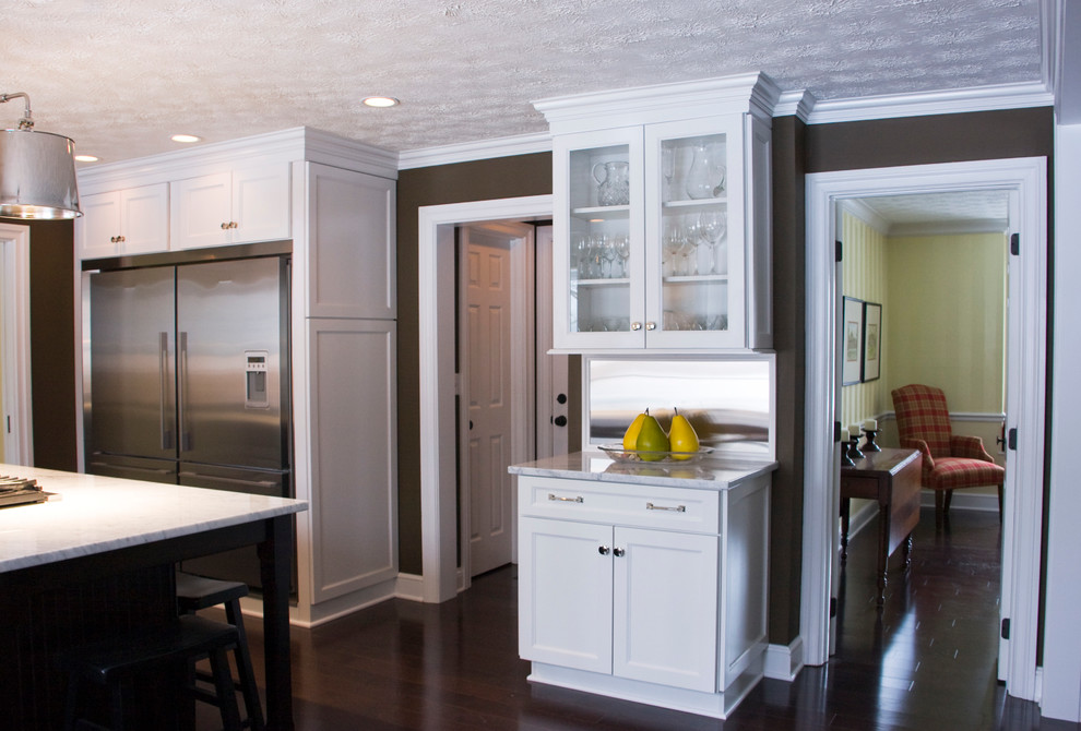 Inspiration for a large transitional dark wood floor kitchen remodel with an undermount sink, shaker cabinets, white cabinets, marble countertops, white backsplash, ceramic backsplash, stainless steel appliances and an island