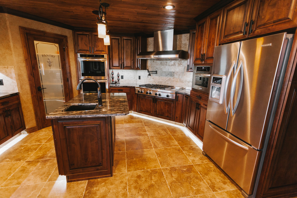 Example of a transitional u-shaped slate floor kitchen pantry design with a double-bowl sink, recessed-panel cabinets, dark wood cabinets, granite countertops, beige backsplash, stone tile backsplash, stainless steel appliances, beige walls and an island