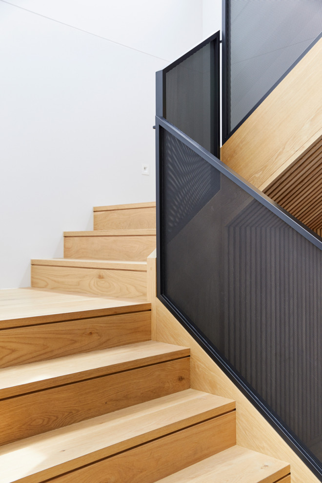 Large contemporary wood u-shaped staircase in Melbourne with wood risers and metal railing.