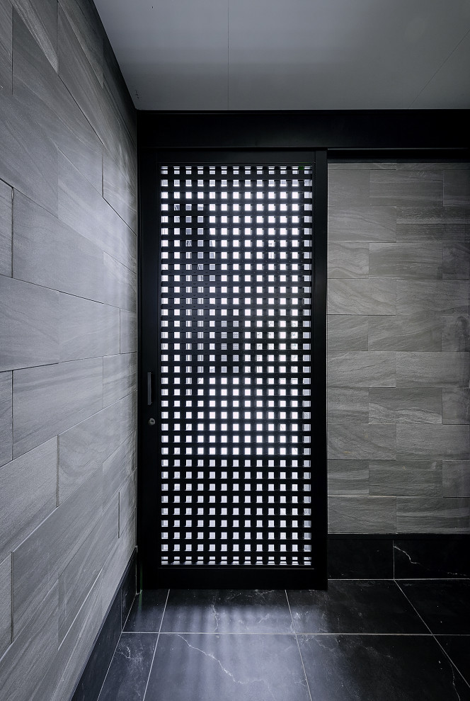 Exempel på en mycket stor entré, med grå väggar, klinkergolv i keramik, en skjutdörr, en svart dörr och svart golv