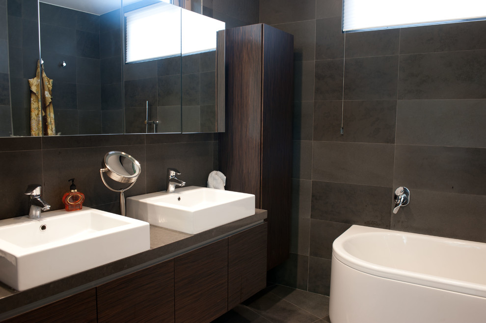 This is an example of a large eclectic master bathroom in Sydney with a trough sink, furniture-like cabinets, dark wood cabinets, quartzite benchtops, a freestanding tub, a corner shower, a one-piece toilet, gray tile, stone tile and white walls.