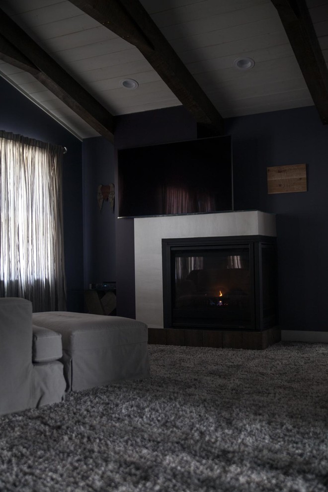 This is an example of a large modern master bedroom in Baltimore with purple walls, carpet, a two-sided fireplace, a wood fireplace surround and grey floor.