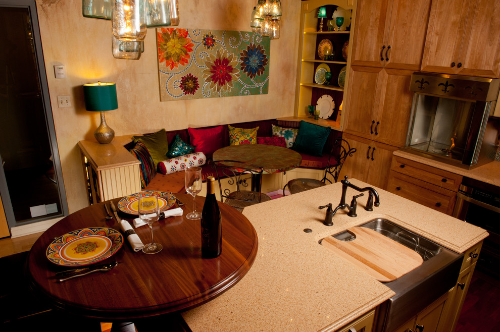 Example of a transitional eat-in kitchen design with a single-bowl sink, recessed-panel cabinets, brown cabinets, quartzite countertops, green backsplash, glass tile backsplash and an island