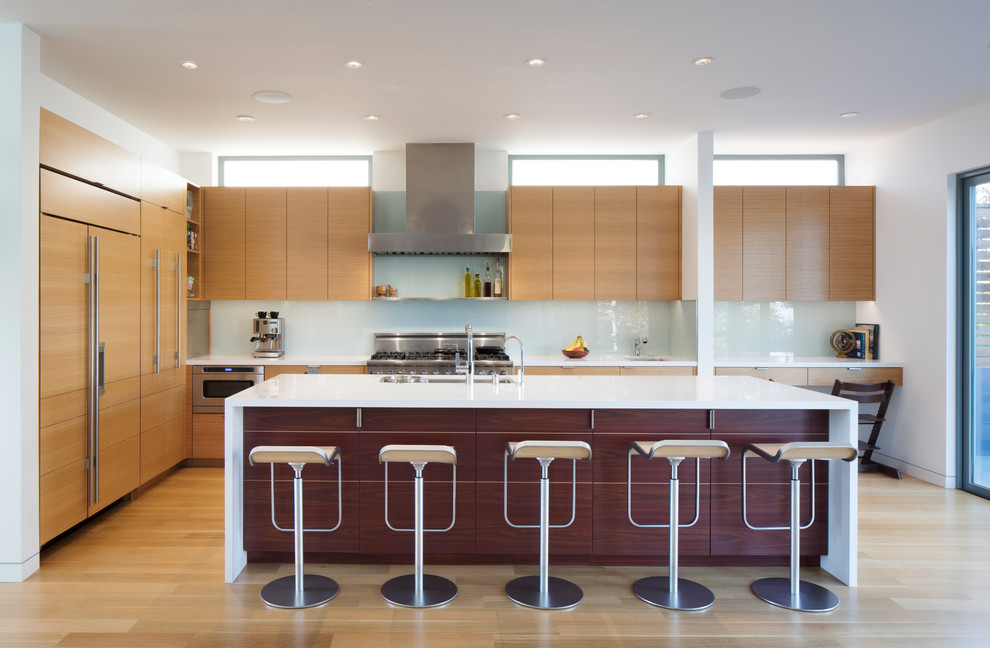 Inspiration for a contemporary galley open plan kitchen in San Francisco with flat-panel cabinets, medium wood cabinets, blue splashback, glass sheet splashback, panelled appliances, light hardwood floors and with island.