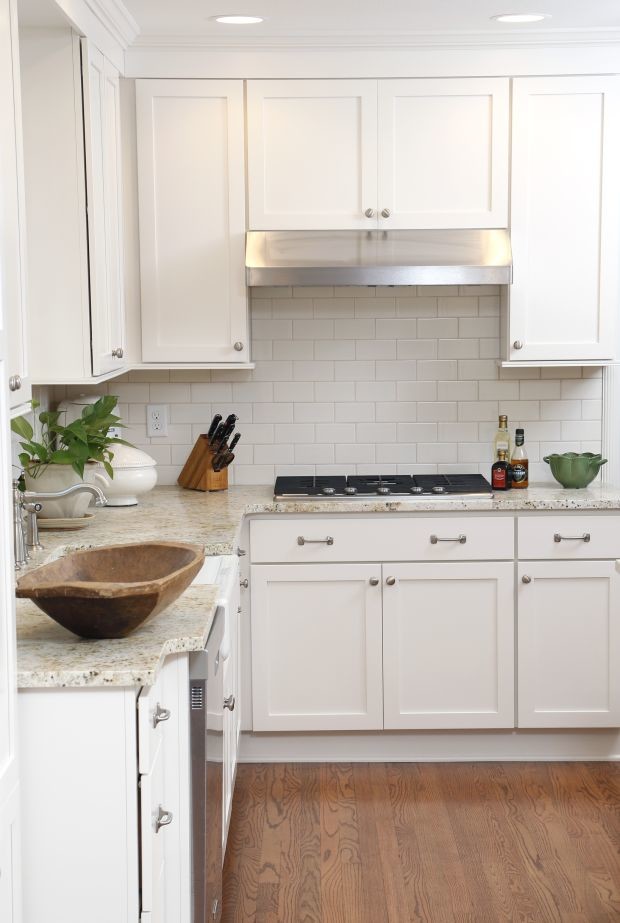 Mid-sized transitional l-shaped dark wood floor eat-in kitchen photo in Cedar Rapids with a farmhouse sink, shaker cabinets, white cabinets, granite countertops, white backsplash, subway tile backsplash, stainless steel appliances and an island
