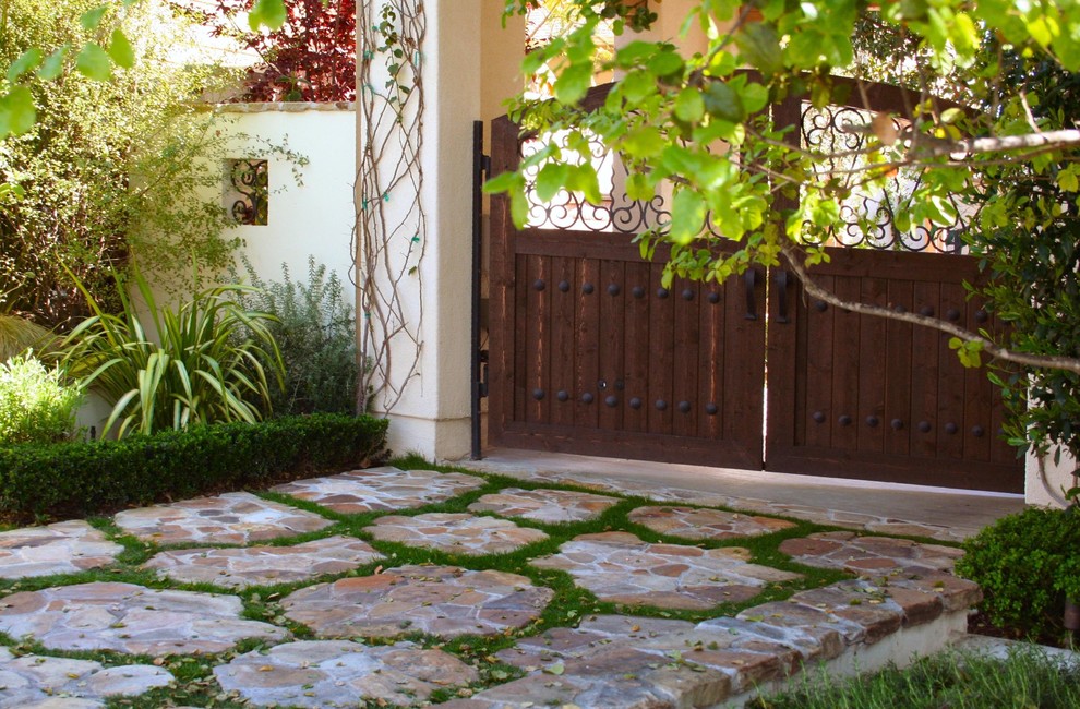 Large mediterranean front yard partial sun driveway in Los Angeles with natural stone pavers.