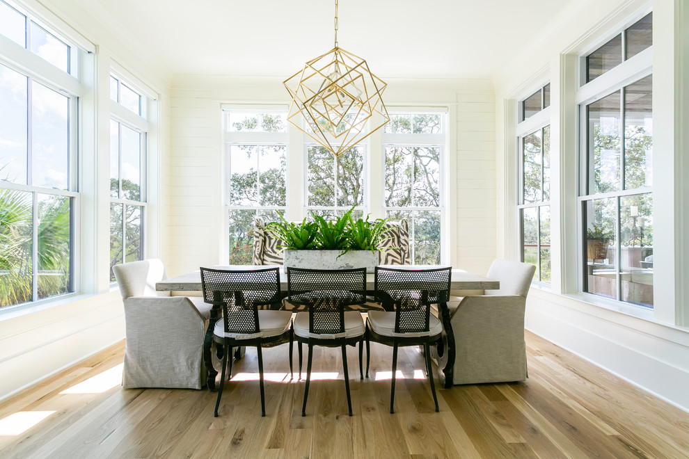 Inspiration for a beach style dining room in Charleston with white walls, light hardwood floors and beige floor.