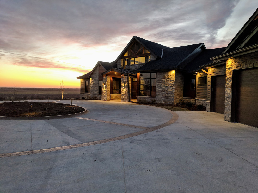 Expansive transitional one-storey brown house exterior in Omaha with stone veneer, a gable roof and a shingle roof.