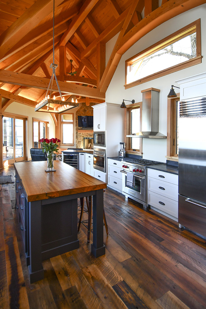 Design ideas for a country galley kitchen in Minneapolis with shaker cabinets, white cabinets, stainless steel appliances, dark hardwood floors, with island, brown floor and black benchtop.