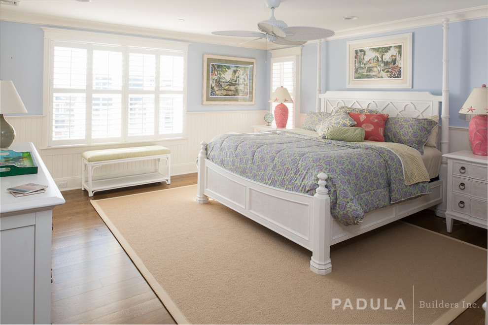 This is an example of a beach style guest bedroom in New York with blue walls and medium hardwood floors.