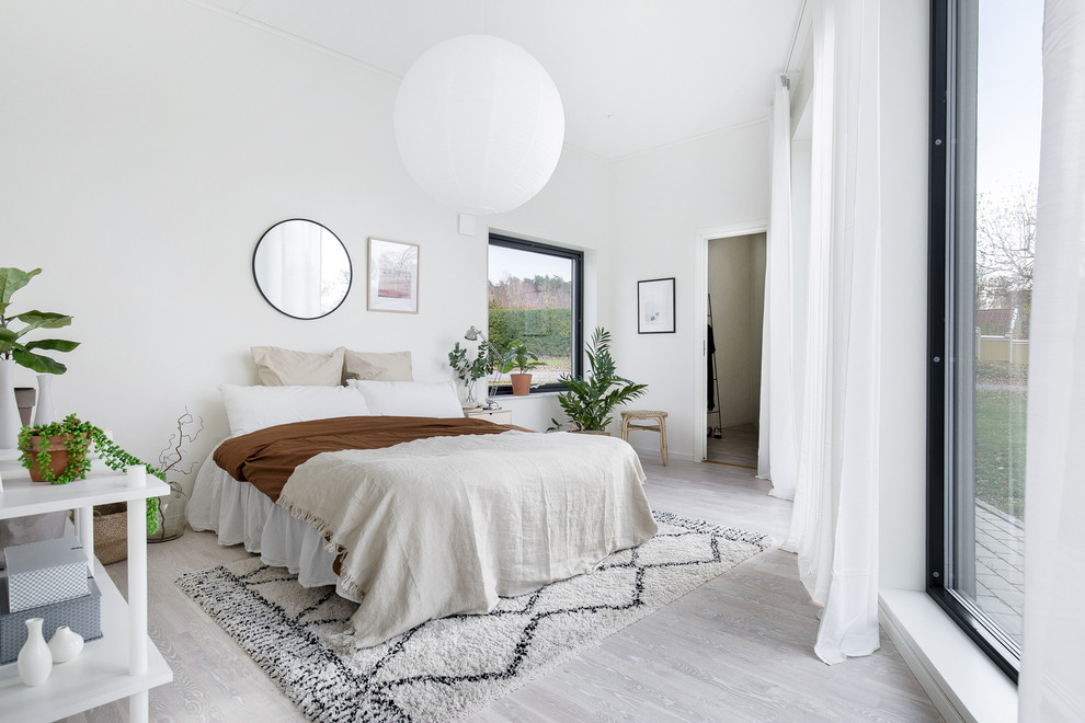 Scandinavian bedroom in Other with white walls, light hardwood floors and grey floor.
