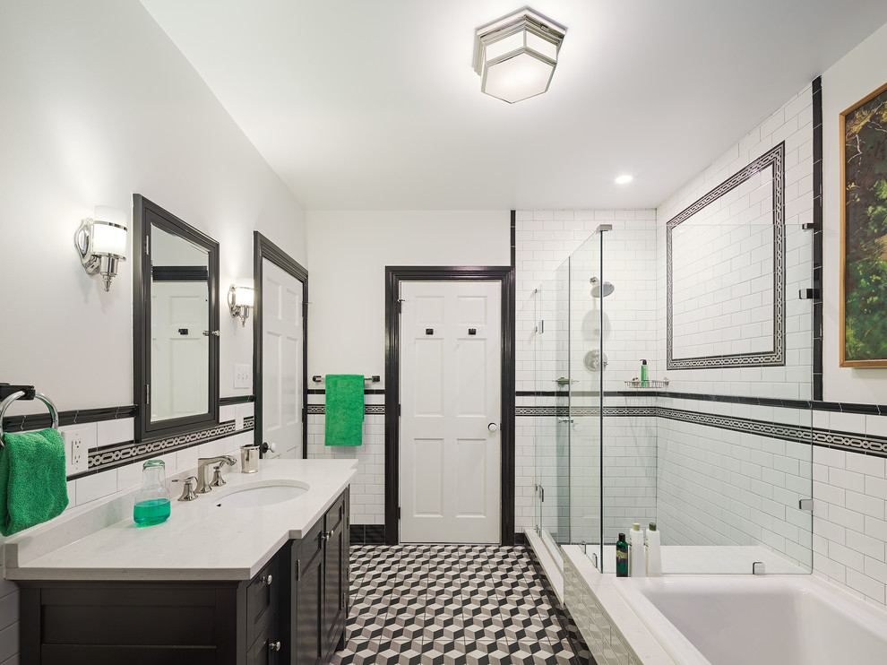 This is an example of a mid-sized traditional master bathroom in Philadelphia with an undermount sink, flat-panel cabinets, engineered quartz benchtops, a drop-in tub, a shower/bathtub combo, a two-piece toilet, multi-coloured tile, cement tile, grey walls and black cabinets.