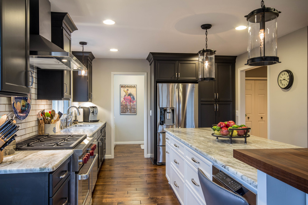Inspiration for a large transitional l-shaped eat-in kitchen in Detroit with an undermount sink, flat-panel cabinets, grey cabinets, granite benchtops, white splashback, subway tile splashback, stainless steel appliances, dark hardwood floors and with island.